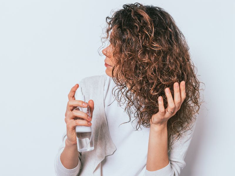 A woman spraying her hair to hydrate