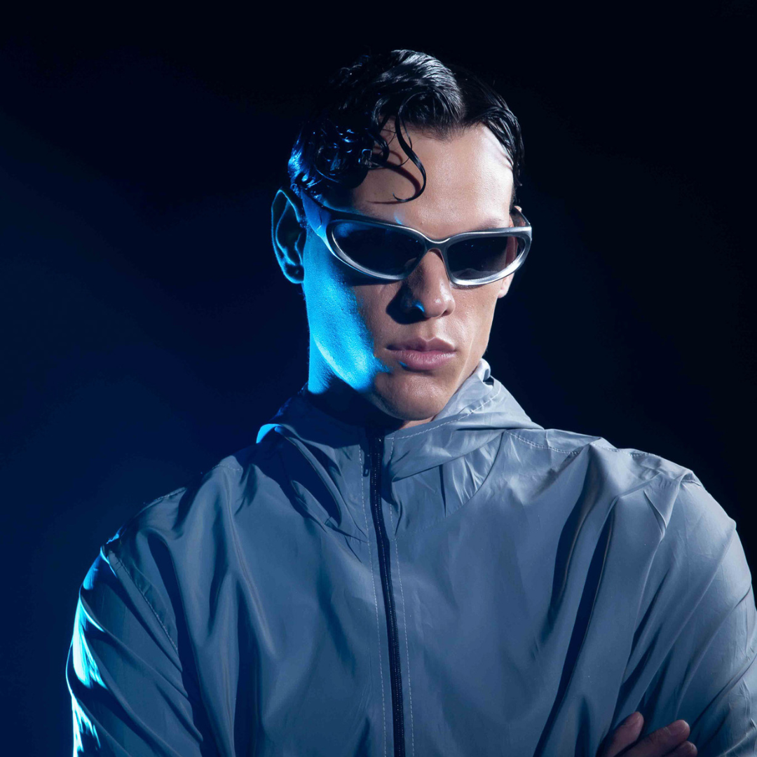 Gelactica model wearing a light gray jacket and sunglasses with a dark background