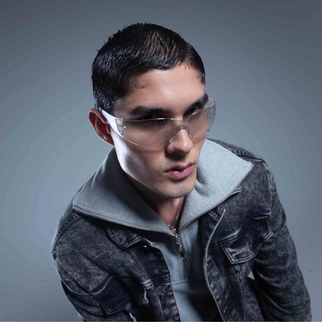 Man wearing clear glasses and a dark jacket against a gray background