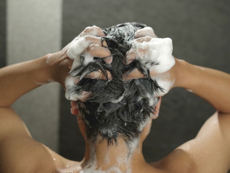 A man using a shampoo on his hair while taking a bath