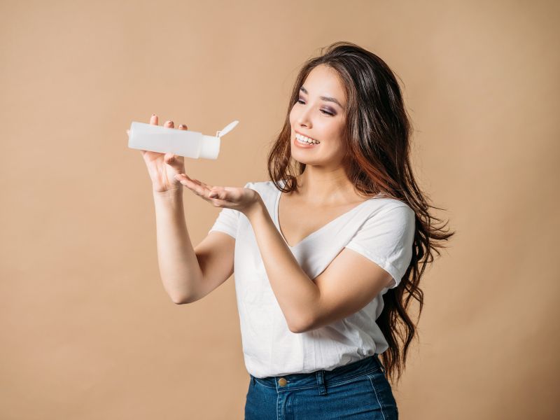 A happy woman pouring hair care product of her palm