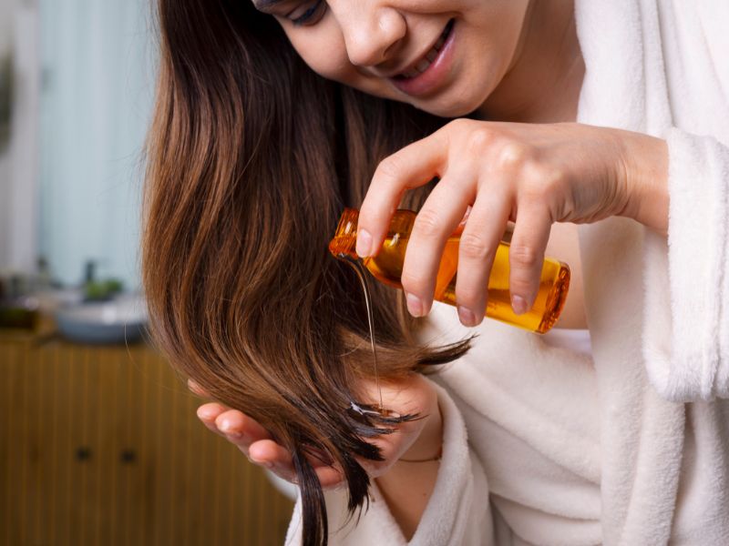 A woman pouring hair oil to the end of her hair