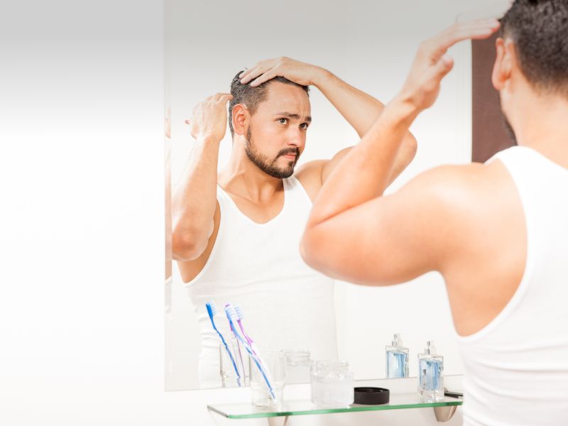 Handsome man styling his hair with gel