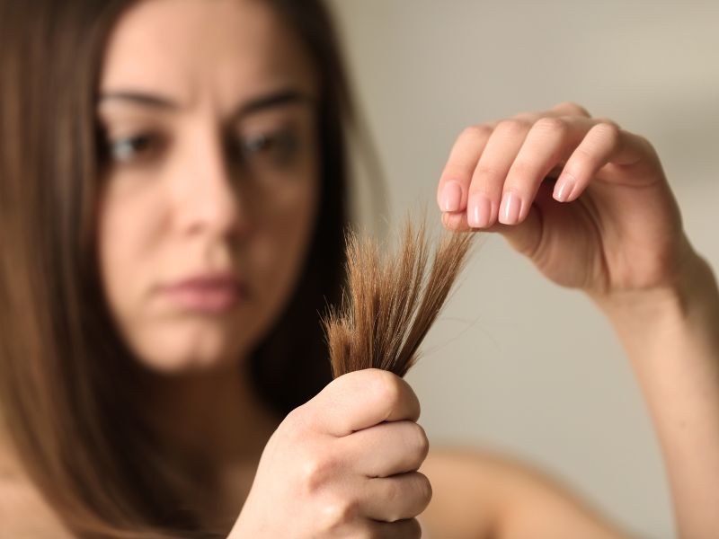 A woman looking her hair with split-ends