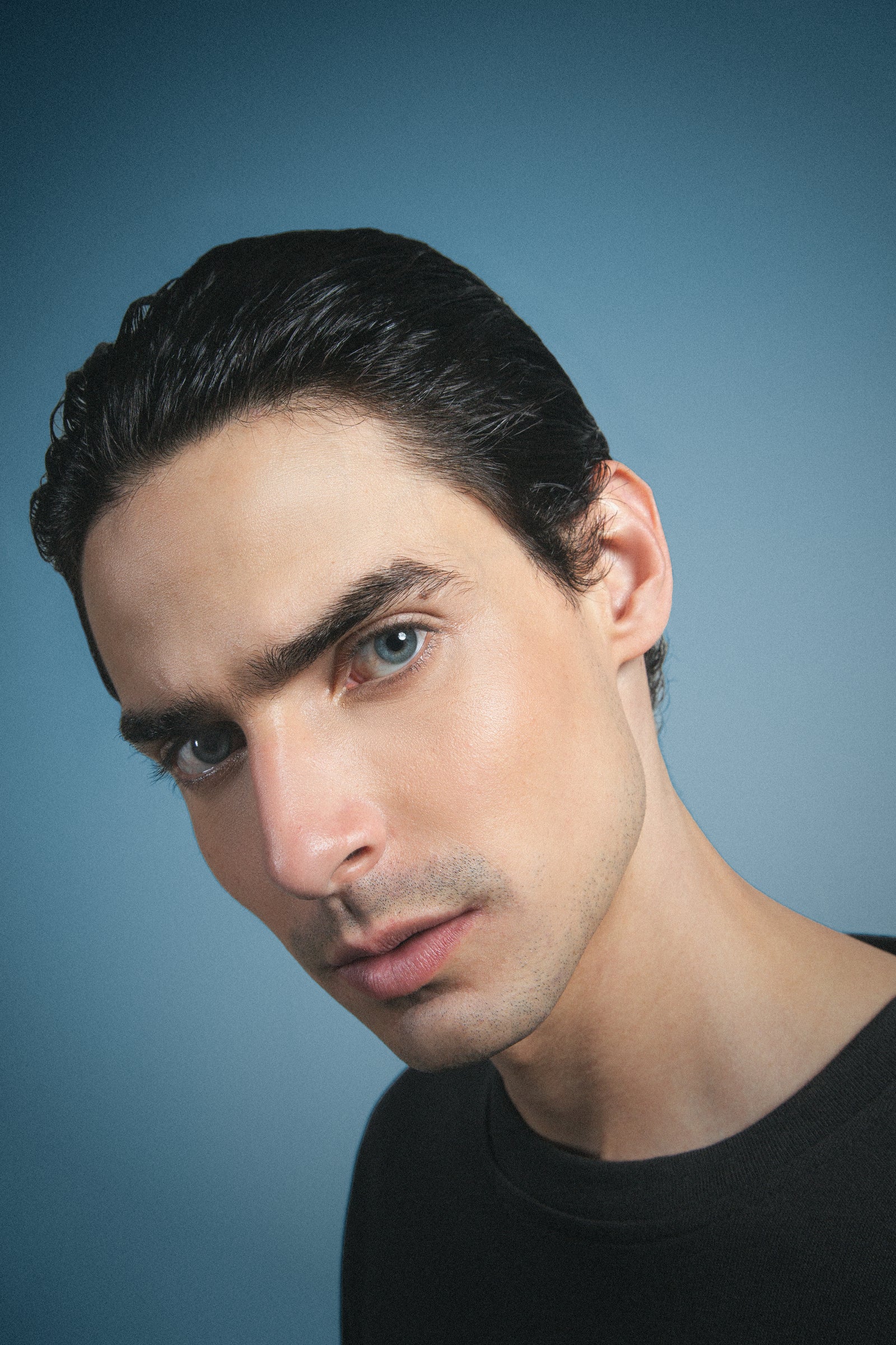 Man with styled hair and beard against a blue background